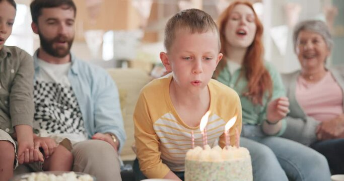 Boy blowing, birthday party or big family with cake in celebration or house party with support or candles. Grandmother, grandfather or excited child eating baked desert with dad, mom or grandparents