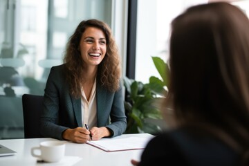 Smiling Female Manager Interviewing an Applicant In Office - obrazy, fototapety, plakaty