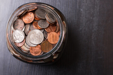 Close up of many different type of coins with jar 