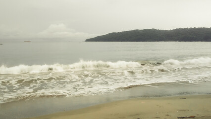 waves wash the sand on the beach and a island behind it