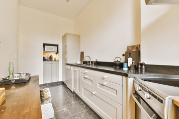 a kitchen with white cabinets and black counter tops in the center of the image is an open door leading into the dining room