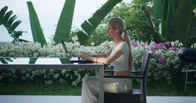 Woman freelancer distant online work. Business woman type on computer outside palm tree cafe. Freelance female using laptop computer, web study outdoor Asia. Digital nomad concept