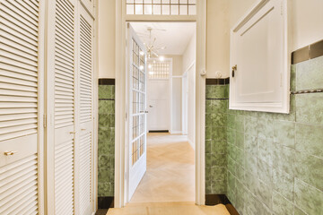 a long hallway with green tiles on the walls and wood flooring in an open space that has been used for storage