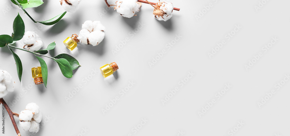 Wall mural Bottles with essential oil and cotton flowers on light background with space for text