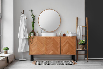 Interior of light bathroom with sink, drawers and mirror