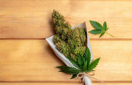 A bouquet of marijuana with a leaf on wooden planks.