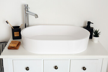 Sink with bath accessories on table near light wall in room