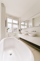 a bathroom with a large bathtub in the middle and two sinks on the other side, there is a window to the right