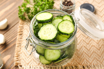 Jar with fresh cut cucumber on table