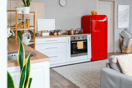 Interior of kitchen with red fridge, counters, sofa and shelving unit