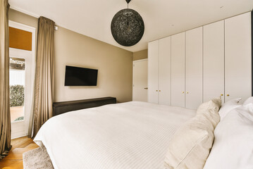 a bedroom with a bed, dressers and tv on the wall in front of the door to the room