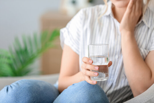 Young woman with dissolved tablet in glass of water at home, closeup