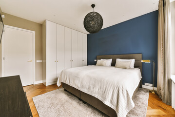 a bedroom with blue walls and white furniture on the floor, along with a large bed in front of it