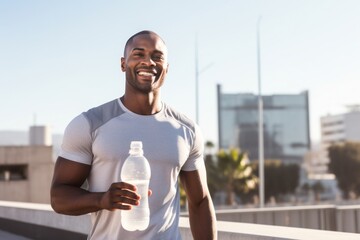 Energetic fitness black american man holding reusable water bottle during workout in gym.