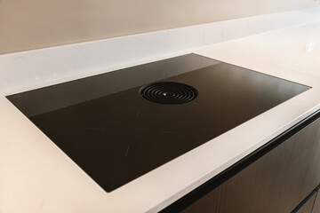 a black and white stove top in a kitchen with an electric range cooker on the left side of the sink