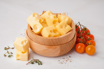 Bowl with pieces of Swiss cheese and tomatoes on white background