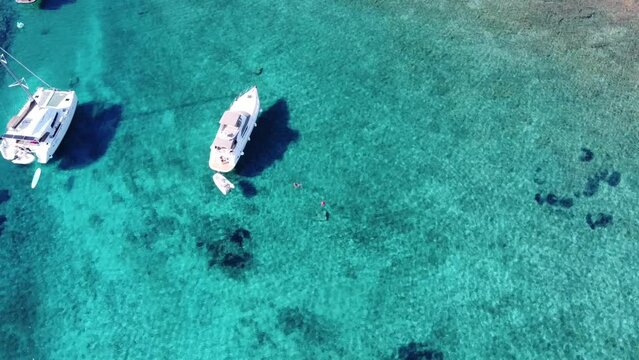 Woman swimming beside Catamaran Yacht anchored in Turquoise transparent water of Blue Lagoon on Veliki Budikovac Island, Croatia. Aerial Orbit