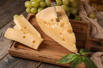Board with tasty Swiss cheese on wooden background
