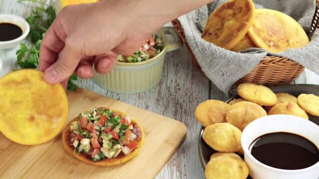 Sopaipillas still life. Video hand placing pebre, zapallo or pumpkin, peregil. in round dish on wooden table, chancaca bowls. Typical Chilean food concept