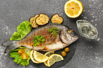 Slate board with tasty grilled dorado fish on grunge background