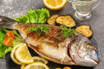 Slate board with tasty grilled dorado fish on grunge background