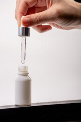 Hand and cosmetic product in tube, bottle, lotion or serum on white background.