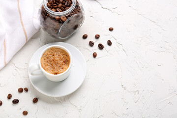 Obraz na płótnie Canvas Cup of hot espresso and jar with coffee beans on white background