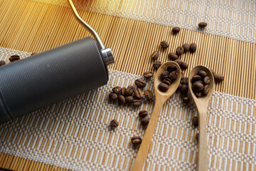 Grinder and coffee beans in a wooden spoon on bamboo mat background for a simple black coffee drip...