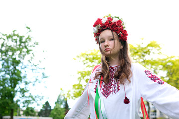 cute young girl teenager ukrainian woman in folk traditional image fixing her hair. the wind blows and develops her curls beautiful wreath with many flowers ribbons nature female natural beauty folk