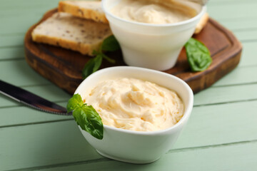 Bowl with tasty cream cheese on green wooden background