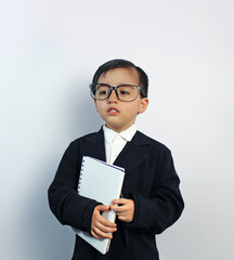 little boy in big man's black suit, wearing large glasses and holding a notebook in his arms, sad who does not want to grow up, on white background
