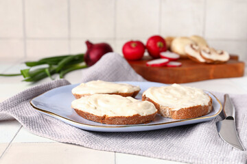 Plate of tasty sandwiches with cream cheese on white tile background
