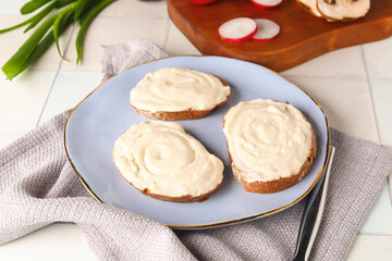 Plate of tasty sandwiches with cream cheese on white tile background