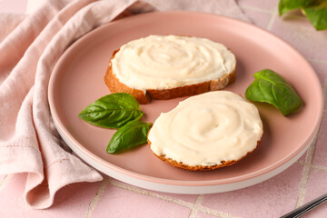 Plate of tasty sandwiches with cream cheese on pink tile background