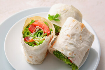 Plates of tasty lavash rolls with tomatoes and greens on light background