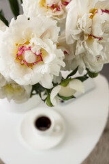 Vase of white peonies on table in room