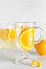 Glass cup of infused water with lemon on light background