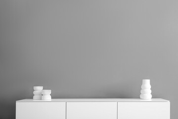 Wooden chest of drawers and decor near grey wall in room