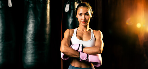 Asian female Muay Thai boxer punch fist in front of camera in ready to fight stance posing at gym...