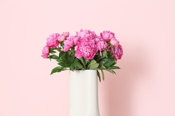 Vase of pink peonies on color background