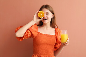 Teenage girl with orange and glass of juice on pink background