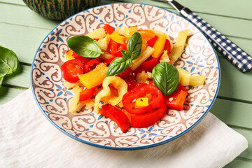 Plate with tasty grilled peppers on green wooden background