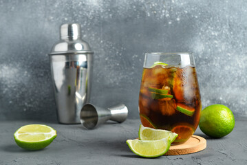 Glass of cold Cuba Libre cocktail on grey background