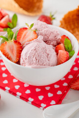 Strawberry ice cream with fresh berries in a bowl on a white wooden background. Selective focus