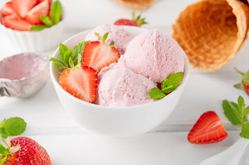 Strawberry ice cream with fresh berries in a bowl on a white wooden background. Selective focus