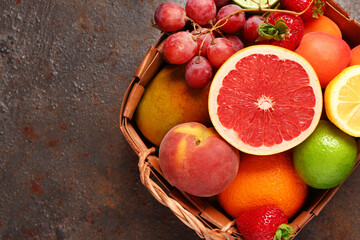 Wicker basket with different fresh fruits on dark table