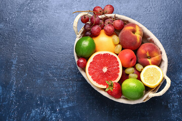 Wicker basket with different fresh fruits on blue background