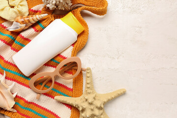 Bikini bra with sunglasses, hair band and bottle of sunscreen cream on white background