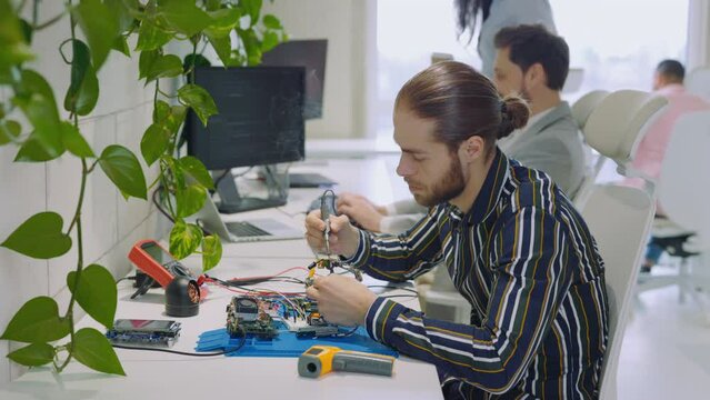 Engineer in Lab Sitting by Desk Soldering Iron Circuit Board. Soldering Technician