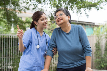Nurse and patient Asian elderly woman with walker. Nurse caring older woman walking with walker outdoor at hospital. Asian nurse taking care old woman with walker in garden at home
